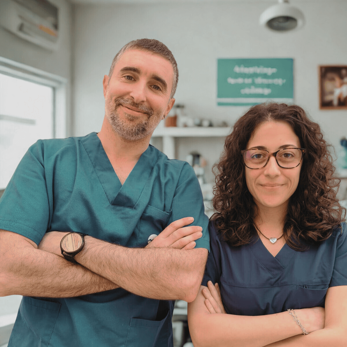 Carme y Xavi, con años de experiencia en el sector, equipo fijo de Lovet Dos profesionales de la salud sonrientes, con uniforme, en un entorno clínico.